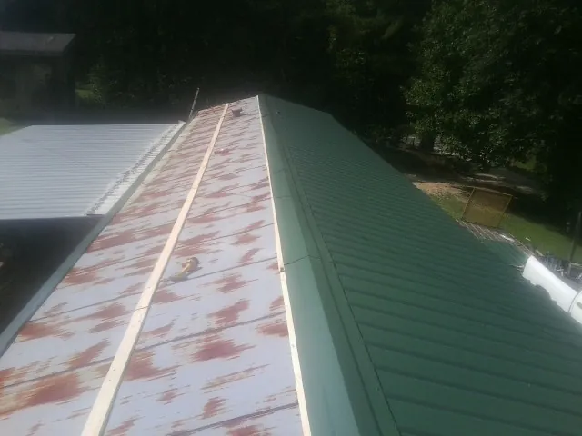 Old rusted panels beside newly installed green metal roofing — Wind Damage Roof Repair by Roofing Brothers in Fredonia