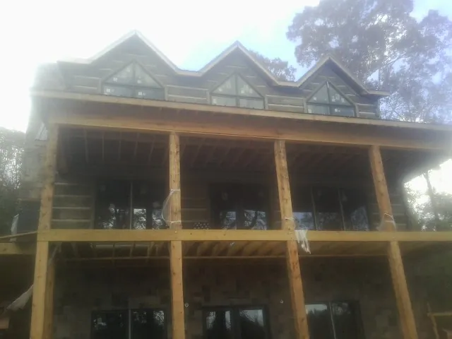 Dormers and porch framing on a large log home under construction — Roof Coating work by our crew in Fredonia